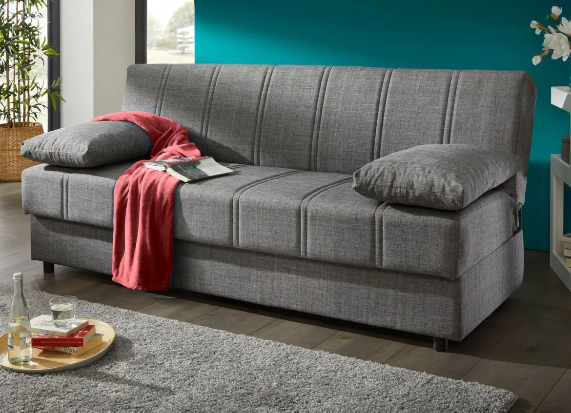 Frei im Raum aufstellbares Schlafsofa mit Dekokissen und Bettkasten