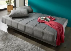 Frei im Raum aufstellbares Schlafsofa mit Dekokissen und Bettkasten